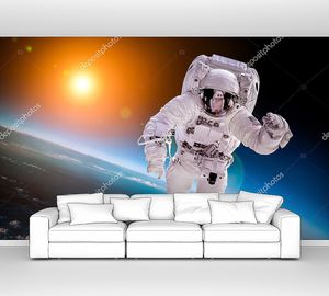 Космонавт в открытом космосе на фоне солнца