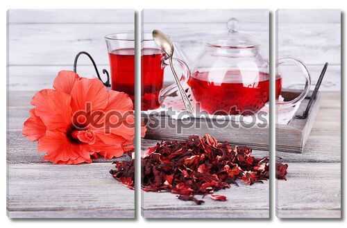 чай из гибискуса в стеклянном чайнике и цветок на цветной салфетки на деревянном фоне