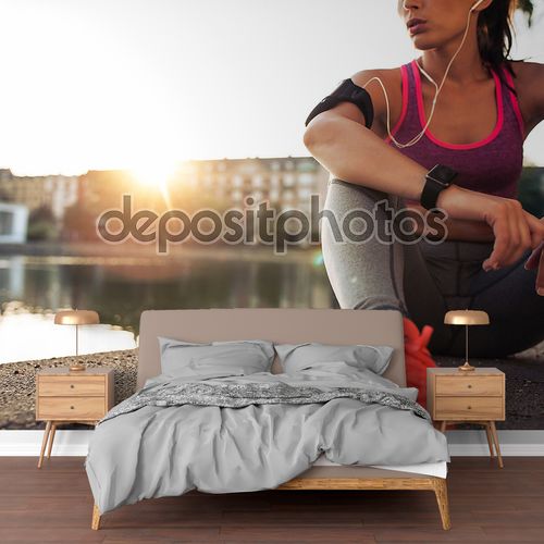 Young woman runner resting along pond