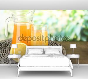 стакан и кувшин апельсинового сока на деревянном столе, на зеленом фоне